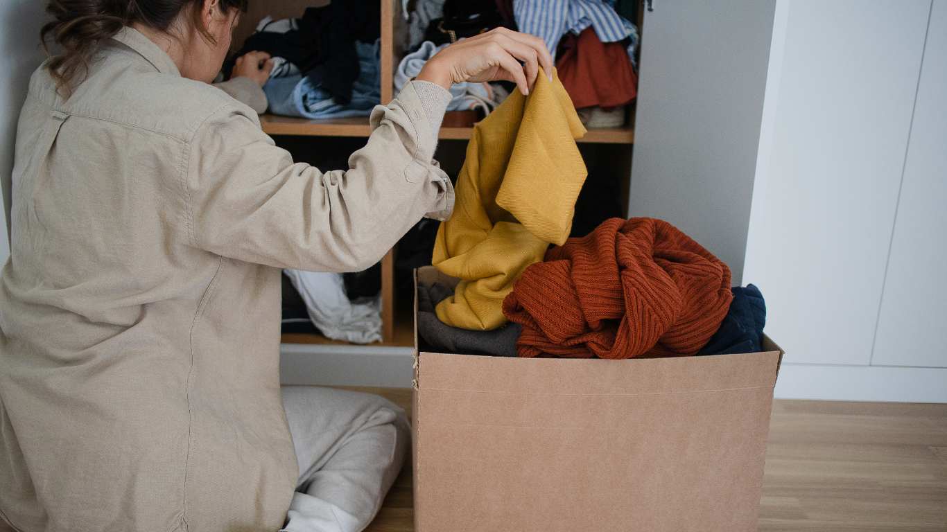 person packing clothing into a box