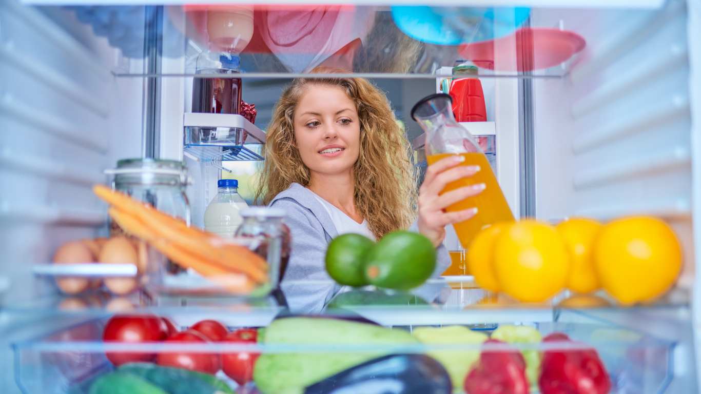 person packing food into refrigerator